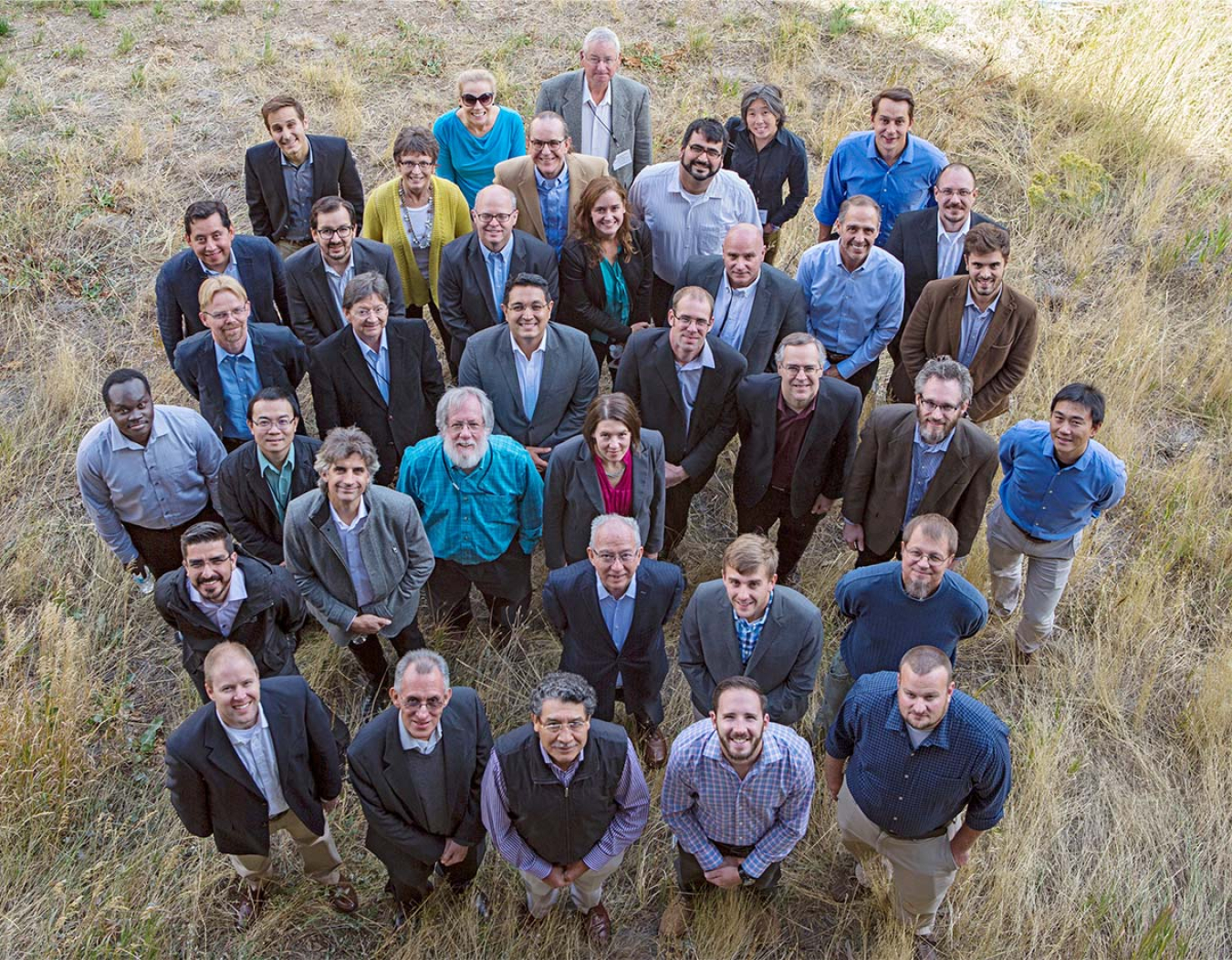 Large group of people standing in the grass and looking up at the camera