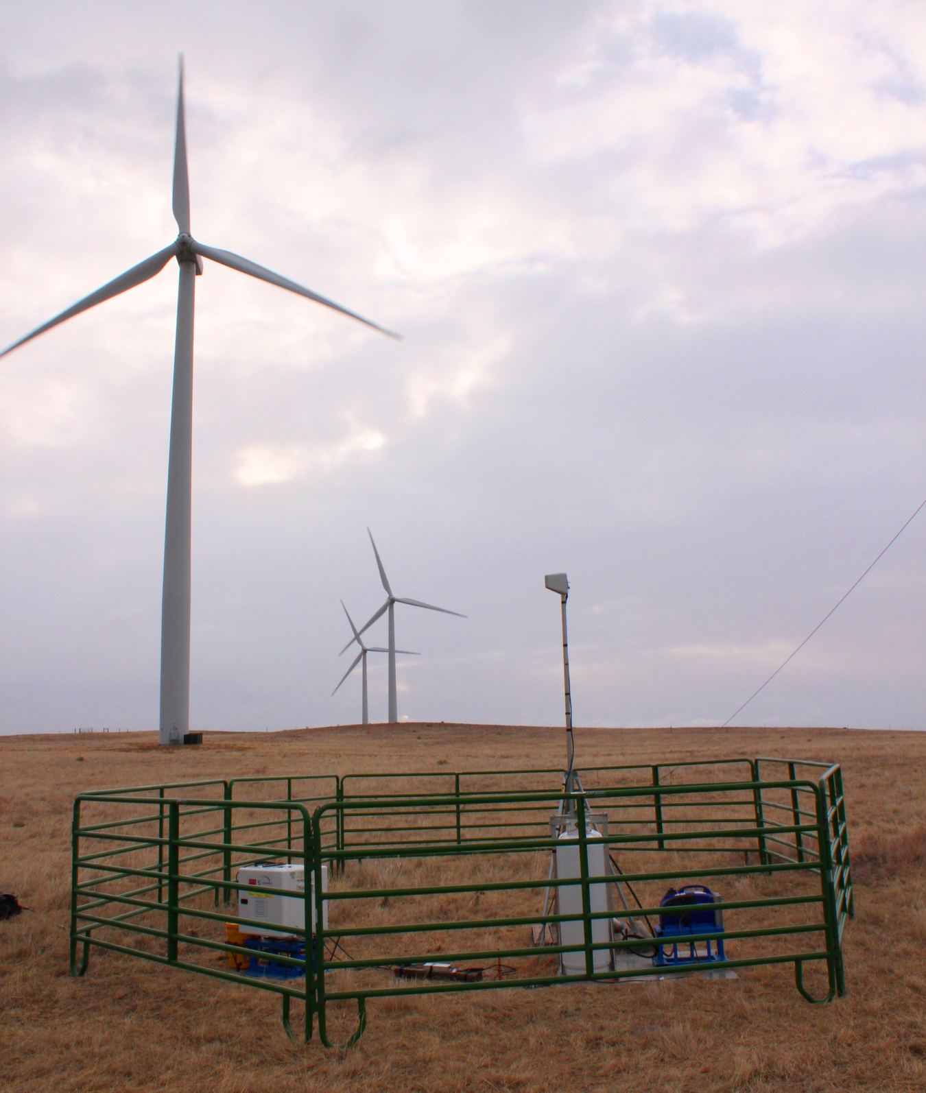 Lidar equipment in the foreground with three wind turbines in the background.