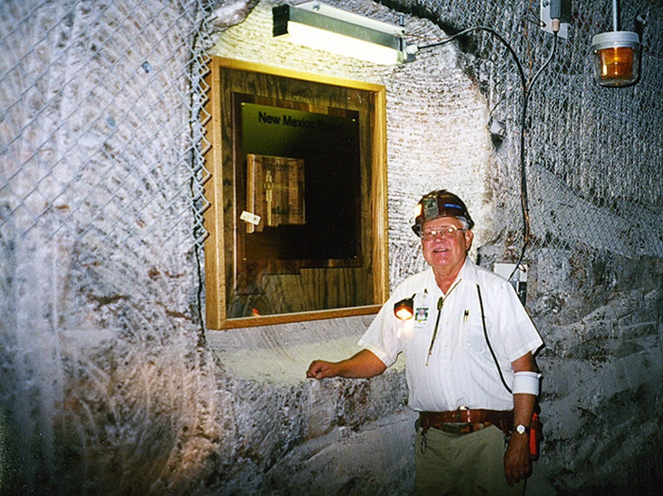 In June 1998, Sandia National Laboratories Waste Isolation Pilot Plant Project (WIPP) Manager Wendell Weart stands in front of the dedication plaque for Room 6 of Panel 1 in the WIPP underground.