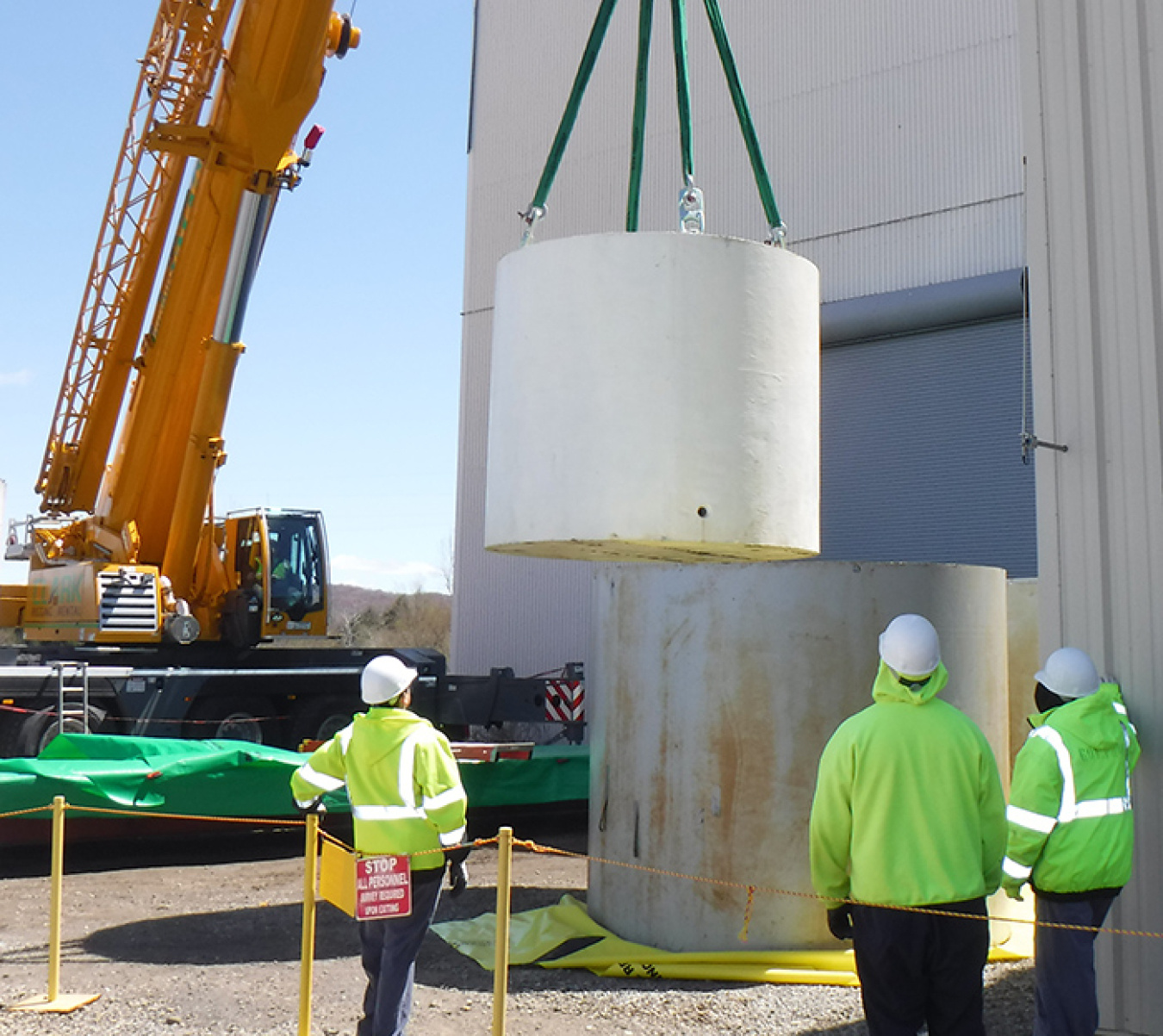 Using a 200-ton crane, workers return a waste container to its exterior steel shield at its new location at an outdoor storage area.