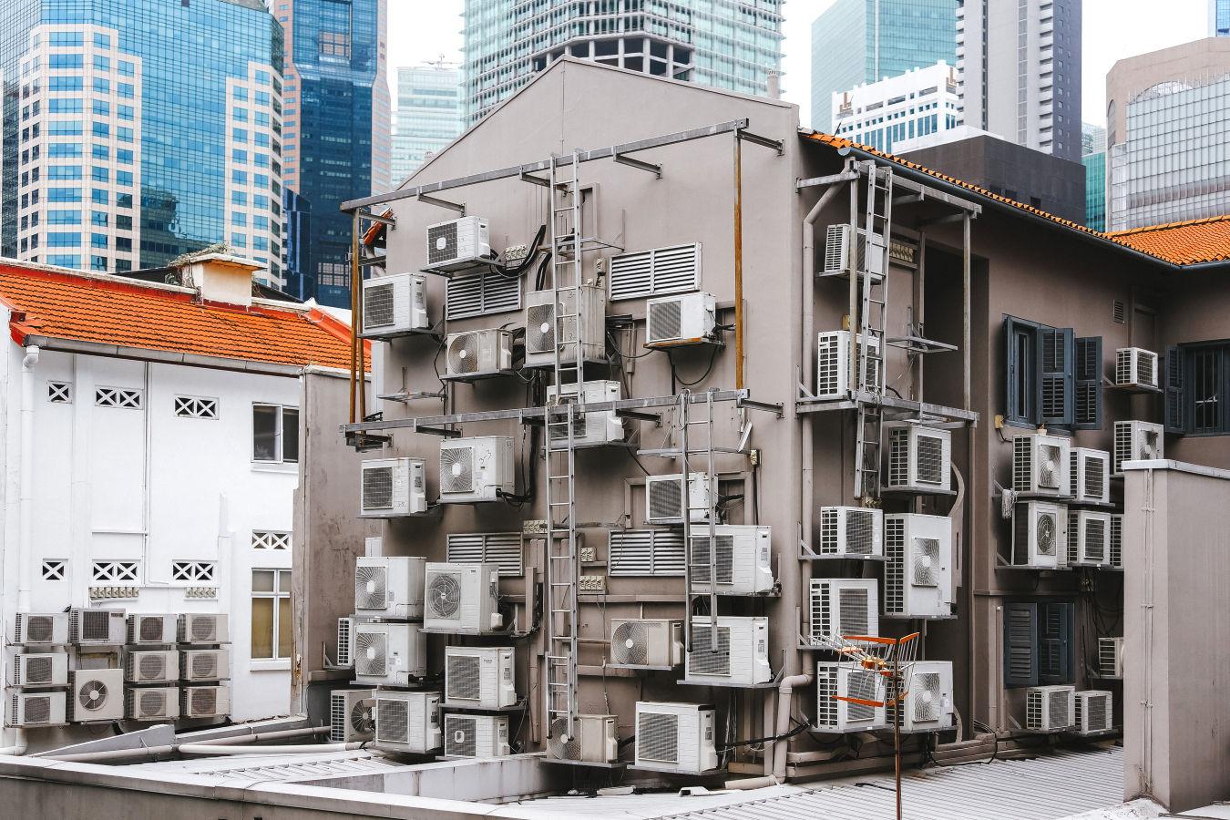 Commercial building in a downtown setting with lots of air conditioning units attached to the outside of it.