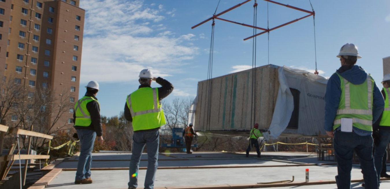 An outdoor shot of a construction site with construction workers in bright vests and hard hats looking at a project.