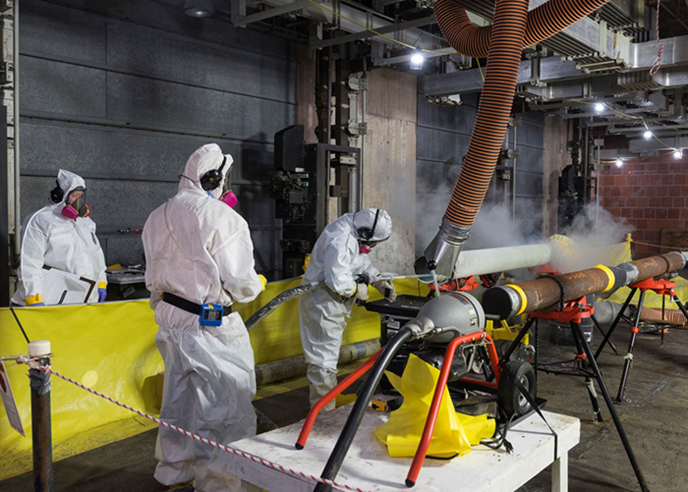 Workers conduct a test before removing crust and scale from the inside of pipes in the Alpha-4 building.