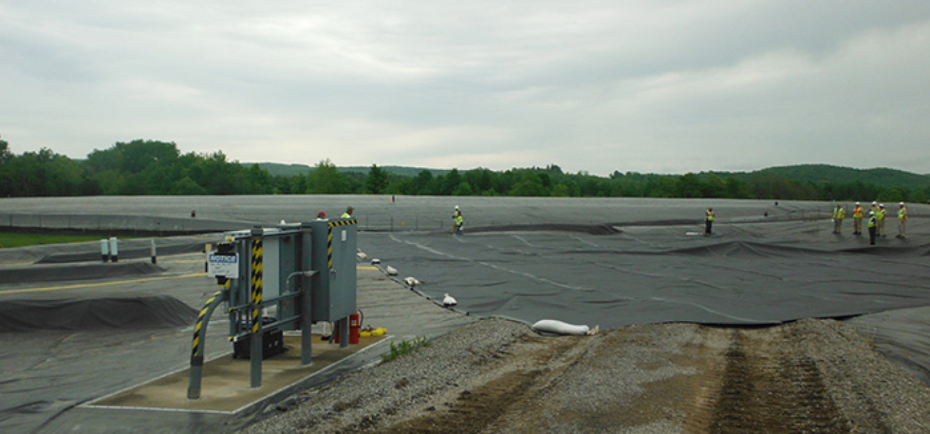 Workers position a temporary protective cover over the pretreatment system facility demolition area until a permanent one is installed later this year.