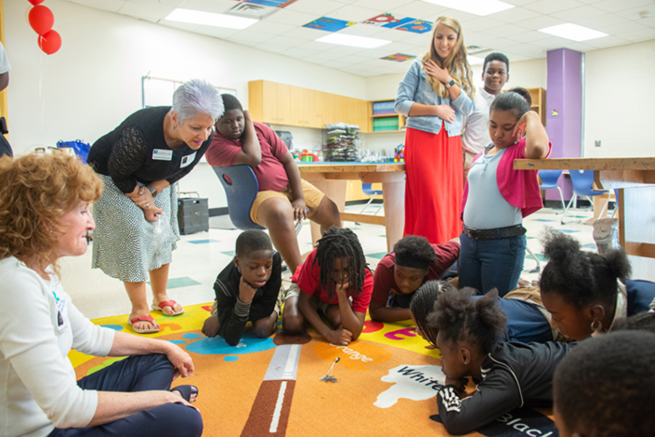 Savannah River Nuclear Solutions employees Kim Mitchell, far left, and Francine Burroughs, second from left, demonstrate how the bess beetle's uniquely clawed feet provide traction and allow the insect to pull more than its own body weight in paper clips.