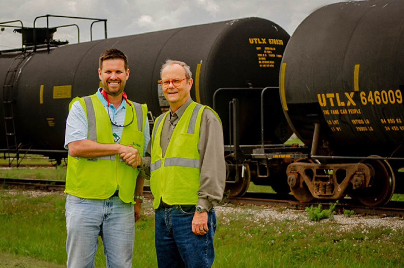 Paducah Area Community Reuse Organization Executive Director Scott Darnell, left, and EM Paducah Site strategic planner Buz Smith stand in front of tank cars at the site.