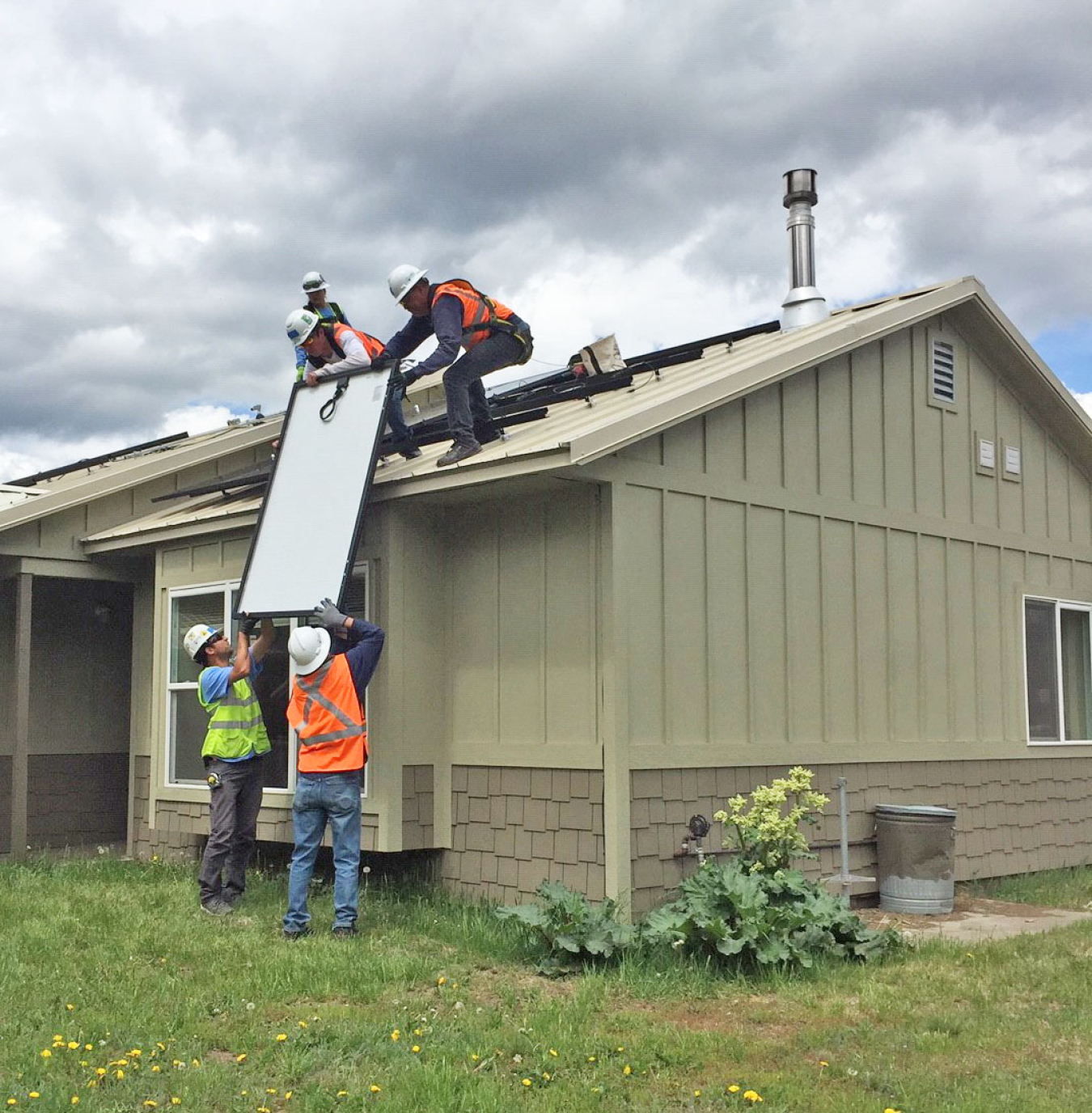 Team of people installing solar panels on a house.