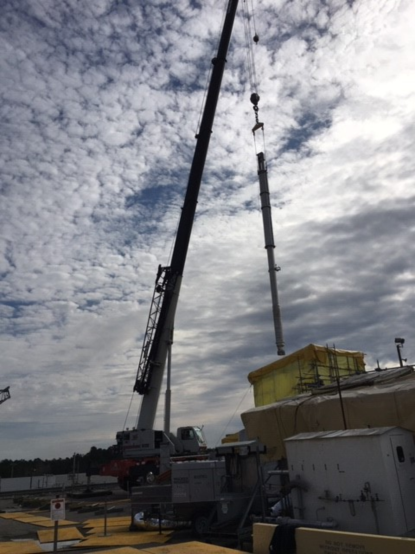Workers use a crane to move a new pump to a Tank 41 riser for installation.