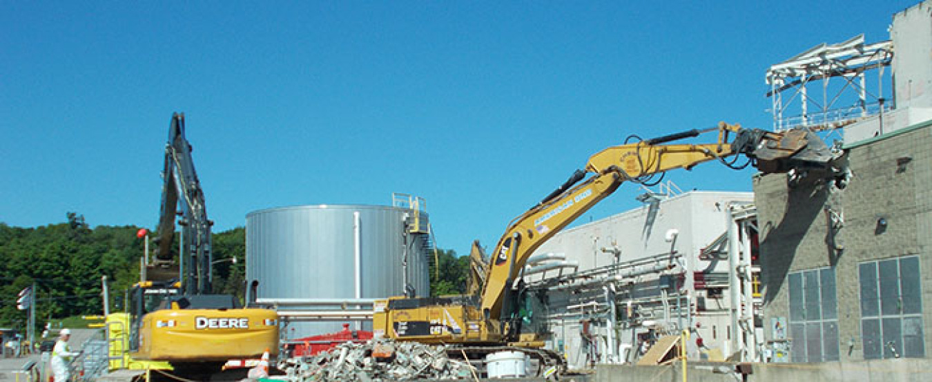 Workers begin demolishing a former utility room extension building at EM’s West Valley Demonstration Project. It was one of seven support buildings of the Main Plant Process Building. Three of those structures remain and are scheduled for demolition.