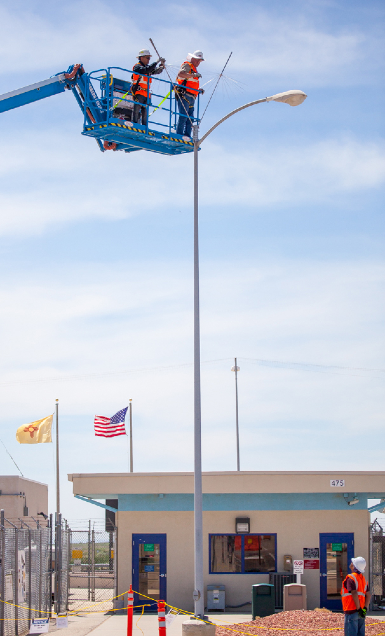 A crew installs small spline balls atop light poles at the Waste Isolation Pilot Plant.