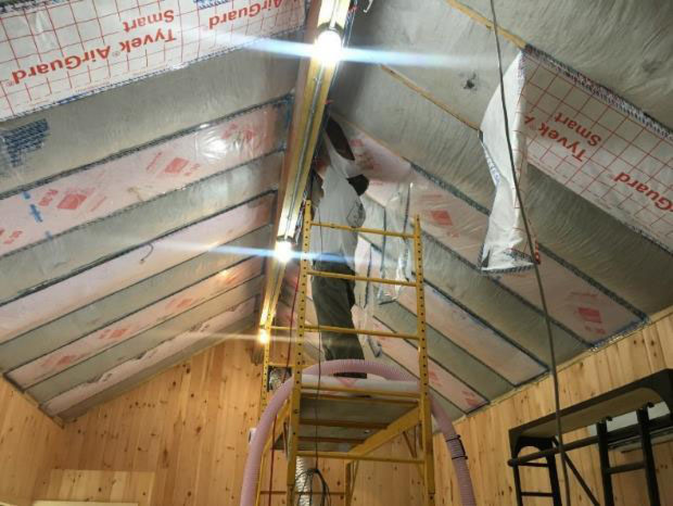 Man standing on ladder working on the roof.