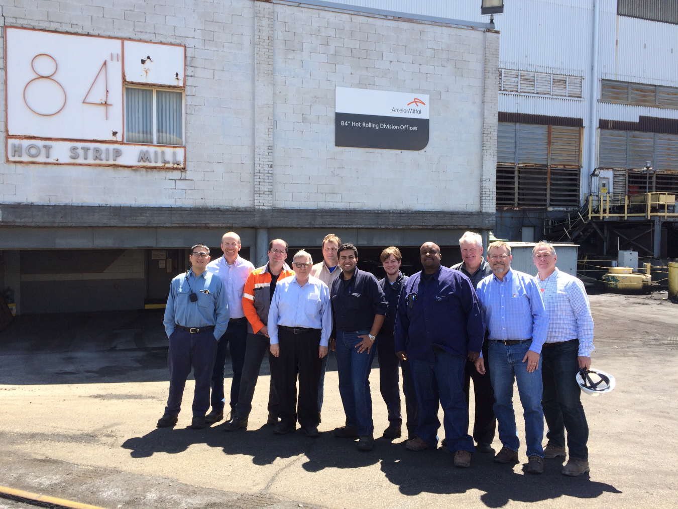 11 men standing in front of the ArcelorMittal building