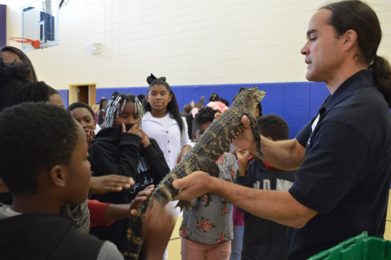 Sean Poppy, outreach coordinator for the University of Georgia’s Savannah River Ecology Laboratory outreach program, shows a juvenile alligator to students at Blakeney Elementary School in Waynesboro, Georgia.