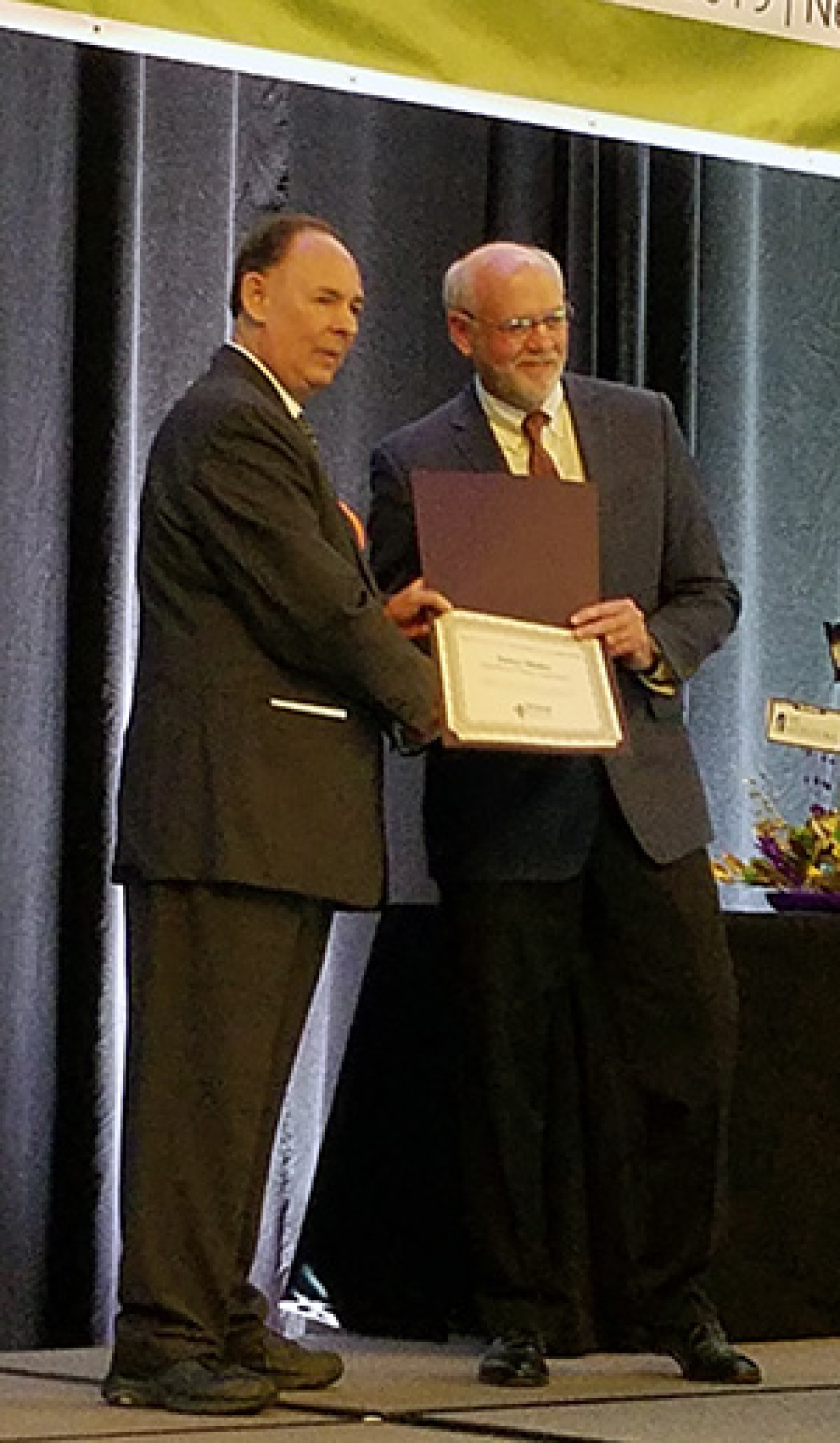Matthew Feldman, control account manager for transportation in the DOE Oak Ridge National Laboratory Office of Integrated Waste Management, presents James Shuler, left, program manager for the DOE Packaging Certification Program.