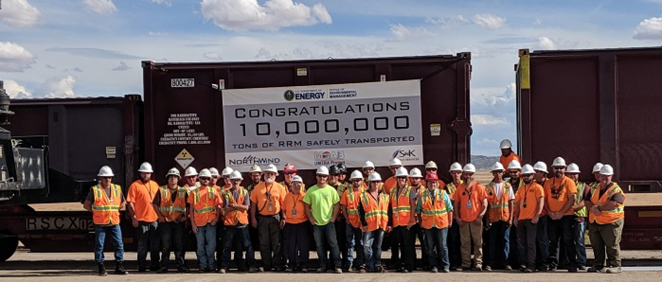 Employees at the Crescent Junction disposal cell site come together to mark the milestone as they await the train carrying the 10 millionth ton from the Moab Uranium Mill Tailings Remedial Action Project.