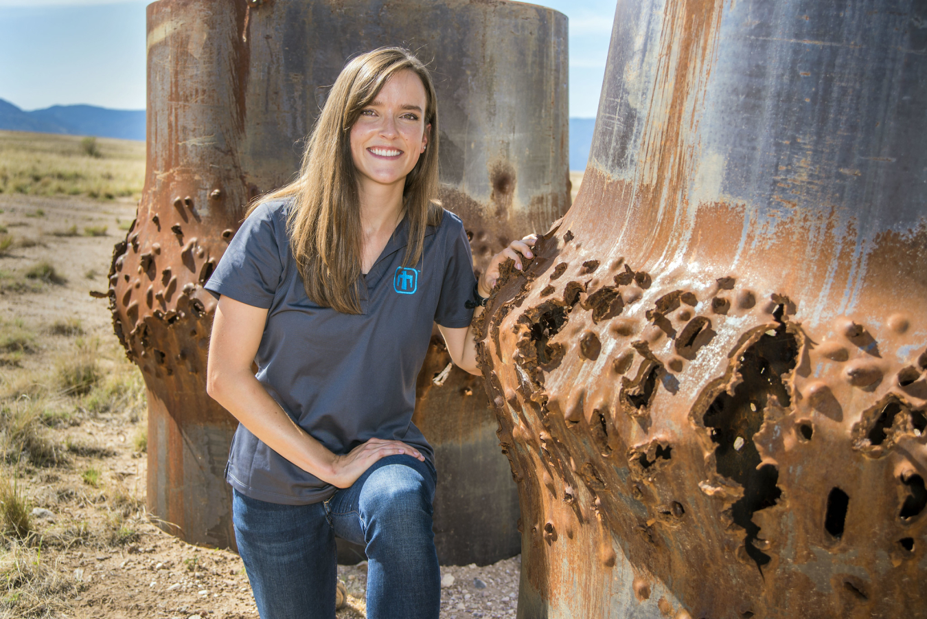 Rebecca Nylen kneels next to blasted steel cylinders, some of her handy work as a computational shock physicist.