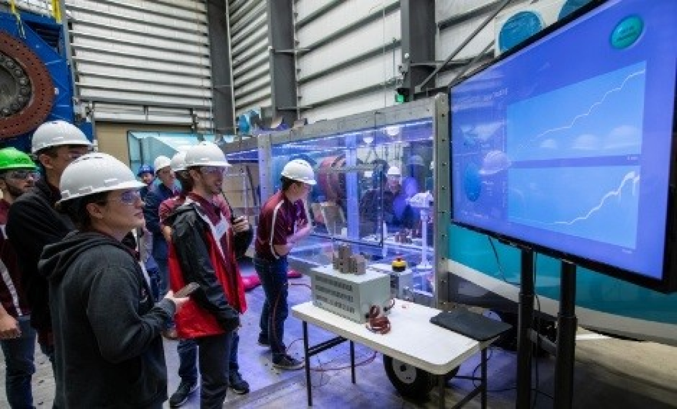 participants in the collegiate wind competition watch their turbine test on a screen.