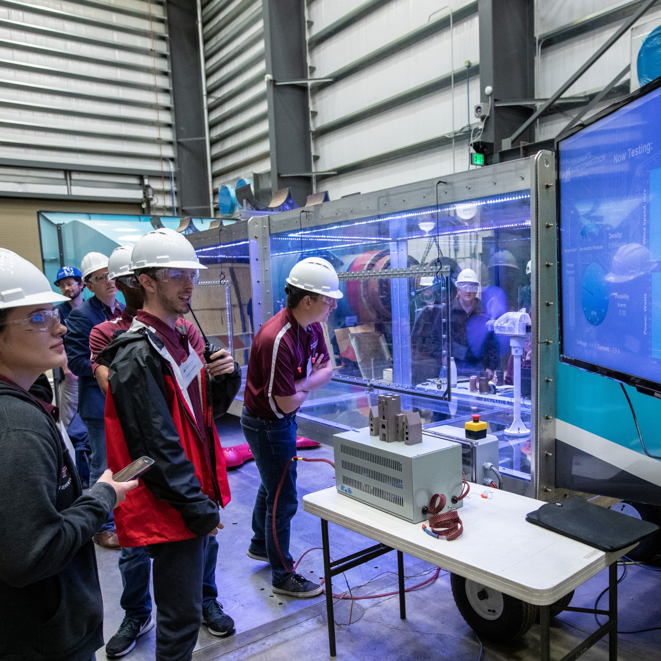 participants in the collegiate wind competition watch their turbine test on a screen.