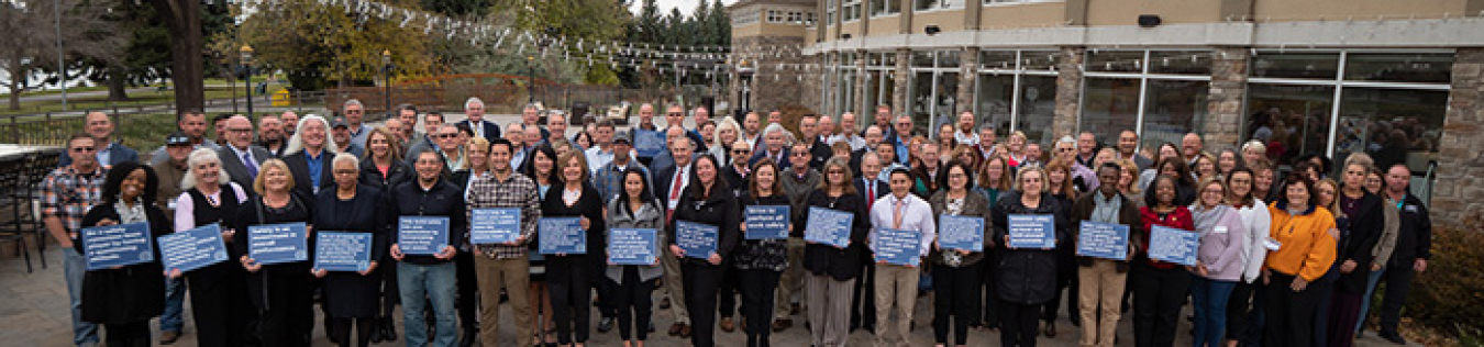 Participants in DOE's recent safety culture workshop in Idaho Falls gather for a photo, with some attendees holding safety messages.