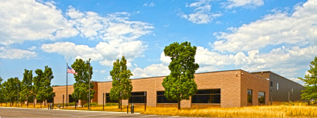 The Clarios Meadowbrook facility. A brown brick building, with trees in front of it.