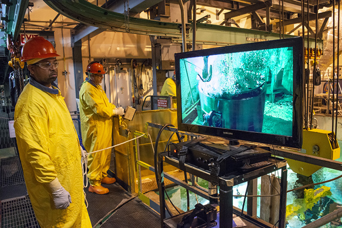 Savannah River Nuclear Solutions employees Erik Tucker, left, and Randy Fanning watch as the inner lid of a High Flux Isotope Reactor (HFIR) spent nuclear fuel shipping cask is removed under water in the L Area disassembly basin.