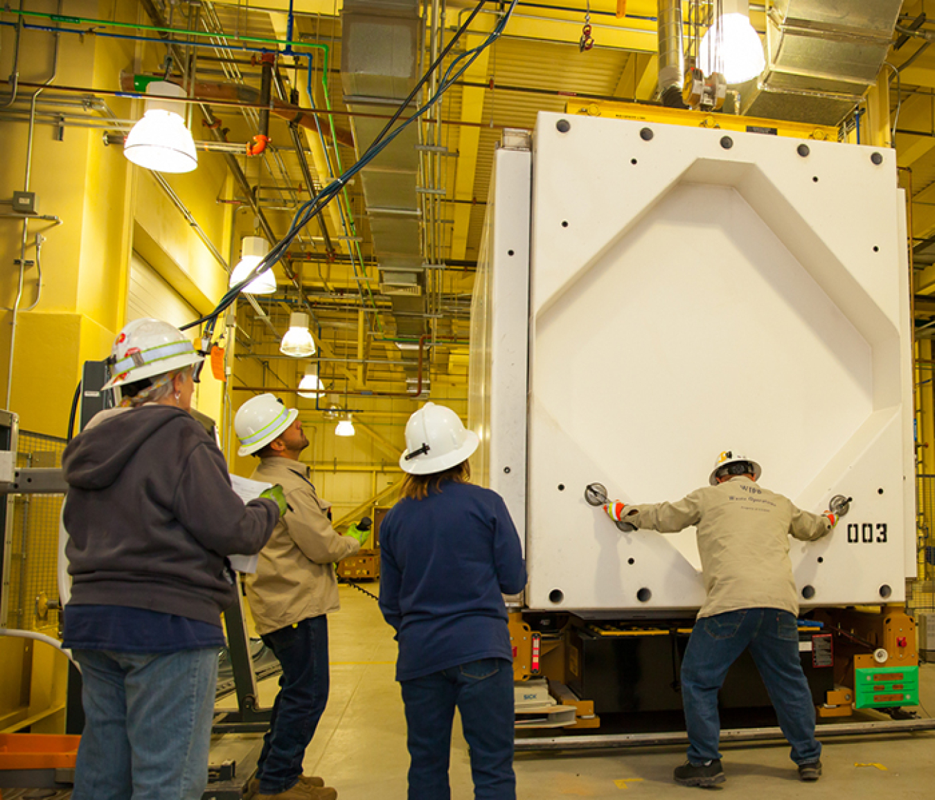 A worker removes the 6,000-pound cover of a Transuranic Package Transporter Model 3 cask during a practice session at the Waste Isolation Pilot Plant.