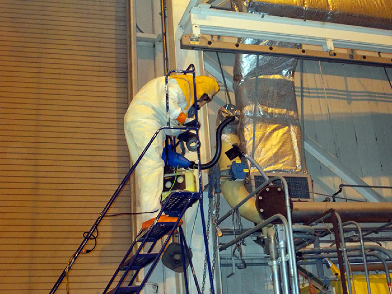 An operator inside the former fuel receiving and storage facility at the West Valley Demonstration Project Site pumps a fogging agent inside a pipe to fix suspected contamination. This work was part of deactivating the building for eventual demolition.