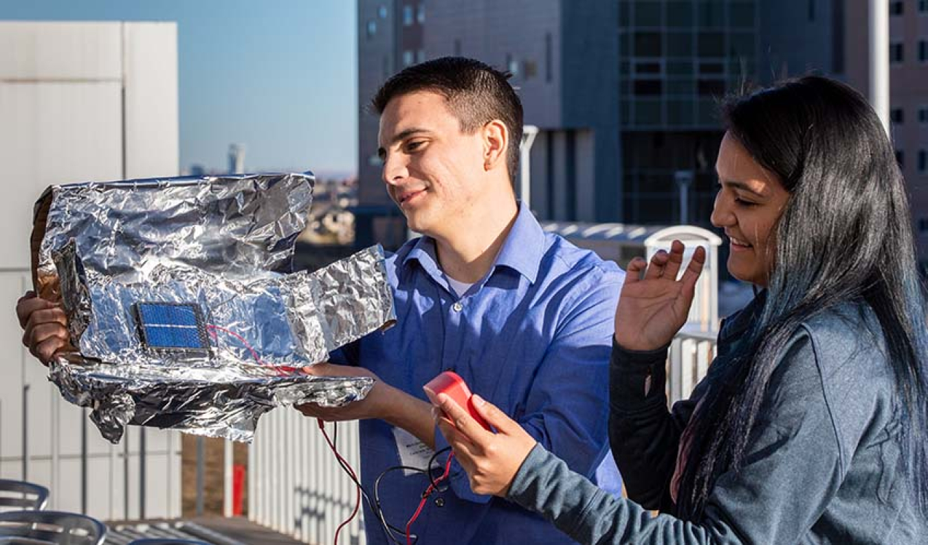 Sean Regalado-Love and Melissa Perez test their team's parabolic collector outside of NREL's Solar Energy Research Facility.