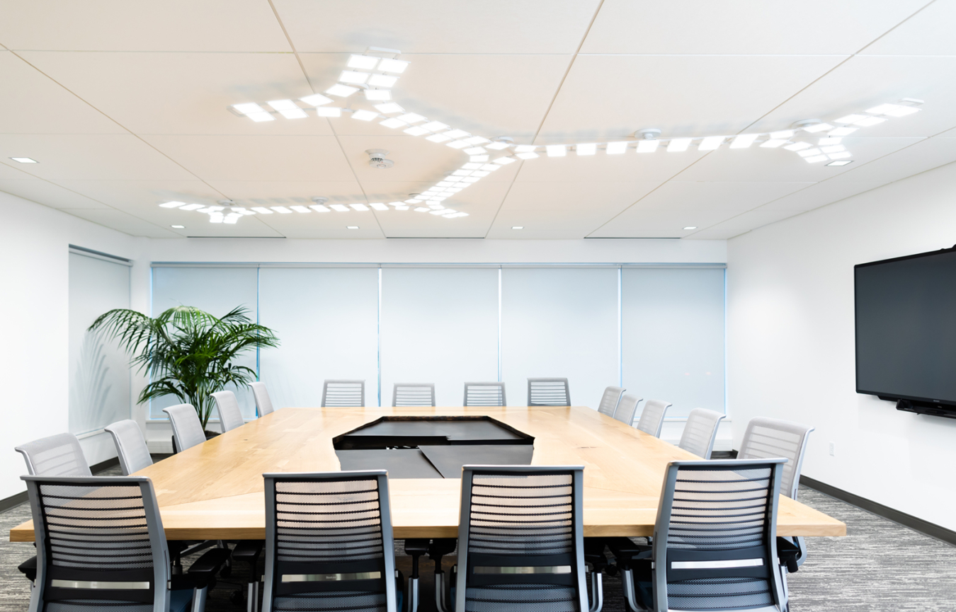 Large conference room table in an office, with empty chairs all around.