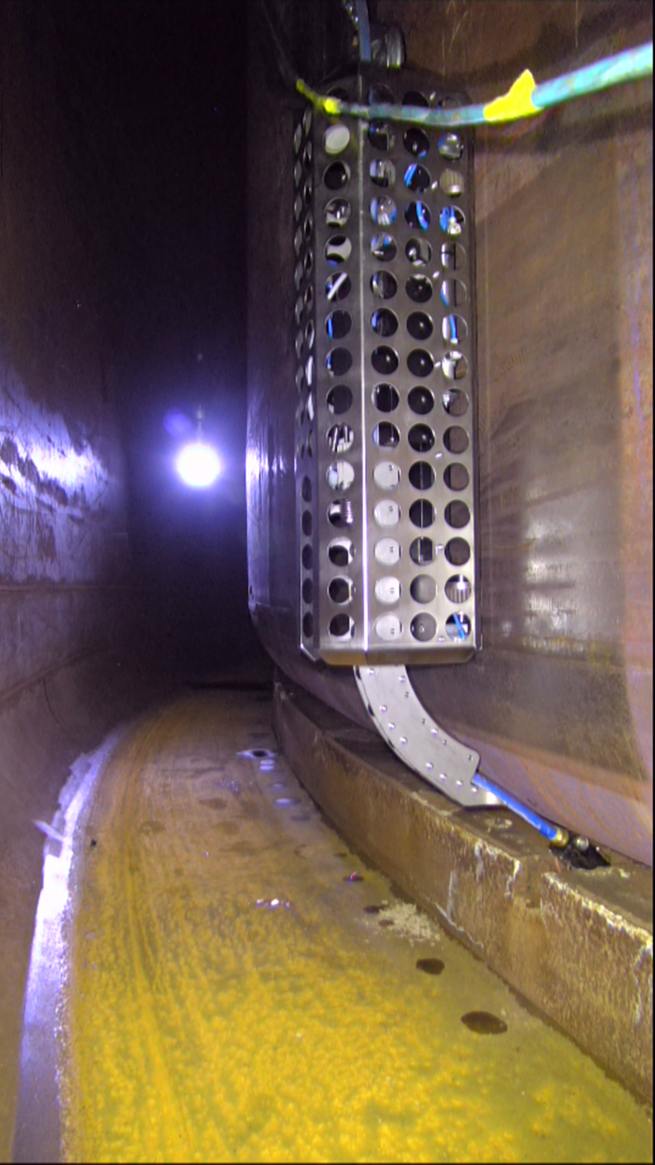 A wall crawler inserts an inspection sensor into a small air slot under the inner shell of a Hanford double-shell tank. In this waste storage tank, operators surveyed six air slots to obtain tank-bottom thickness readings at multiple locations.