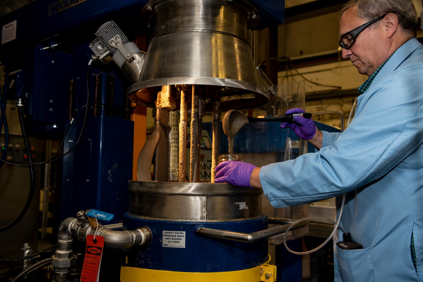 A scientist adding spent grain to a hydrothermal liquefaction system