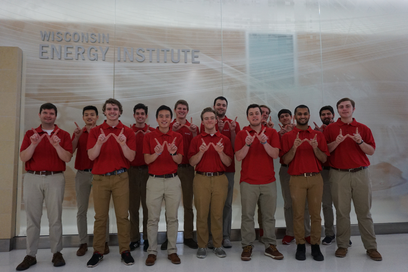 a group of men pose making the letter "W" with their fingers.