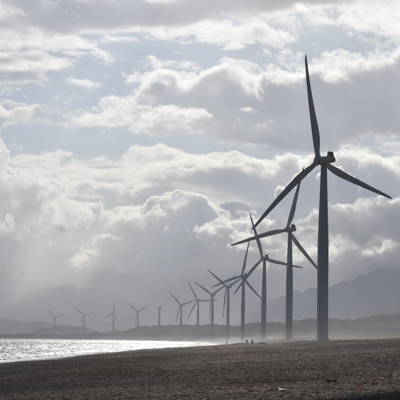 View of a wind farm along a foggy shoreline.