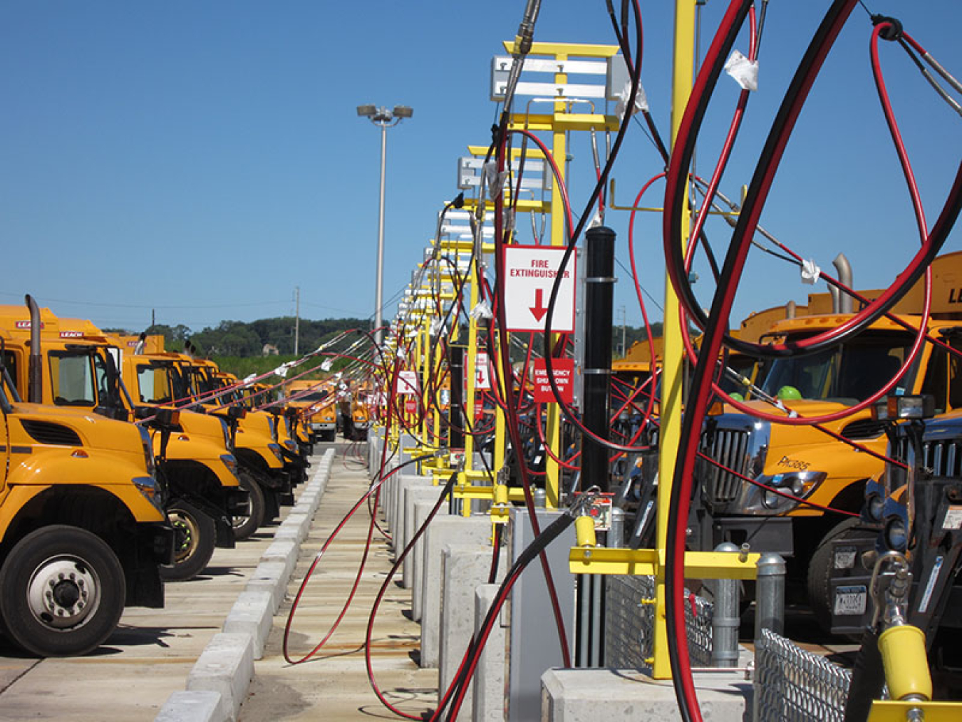 Two rows of trucks plugged into charging stations.