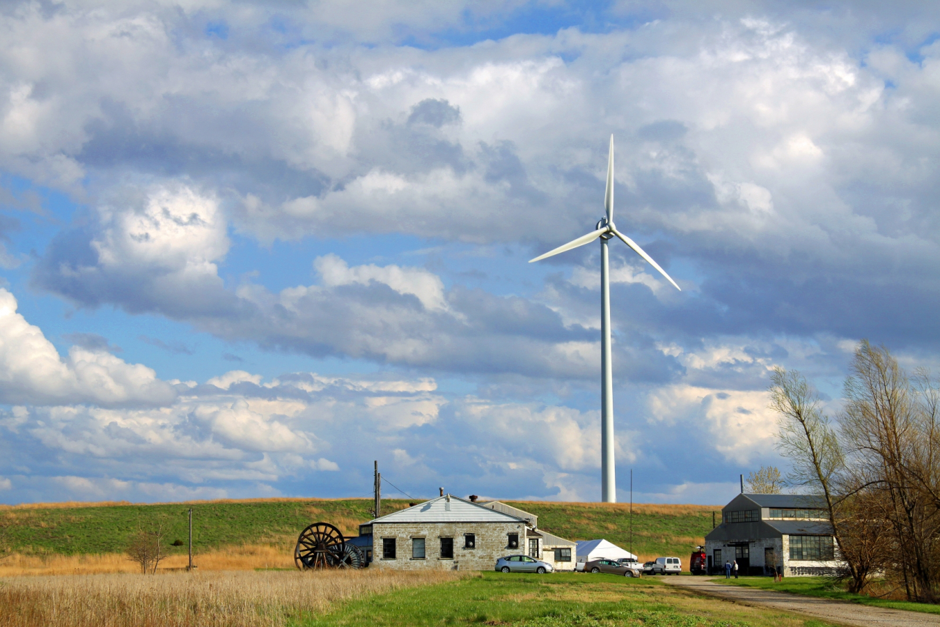 wind turbine on farmland against a cloudy but blue sky.