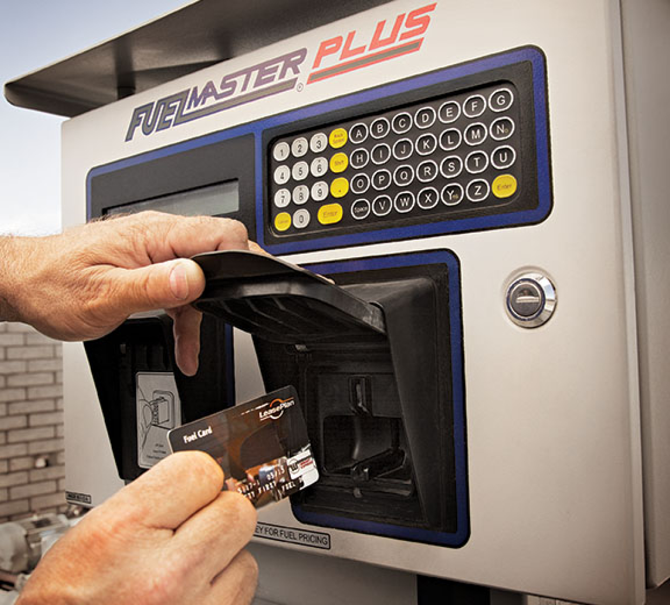 Hand inserts a credit card into a FuelMaster Plus payment machine.