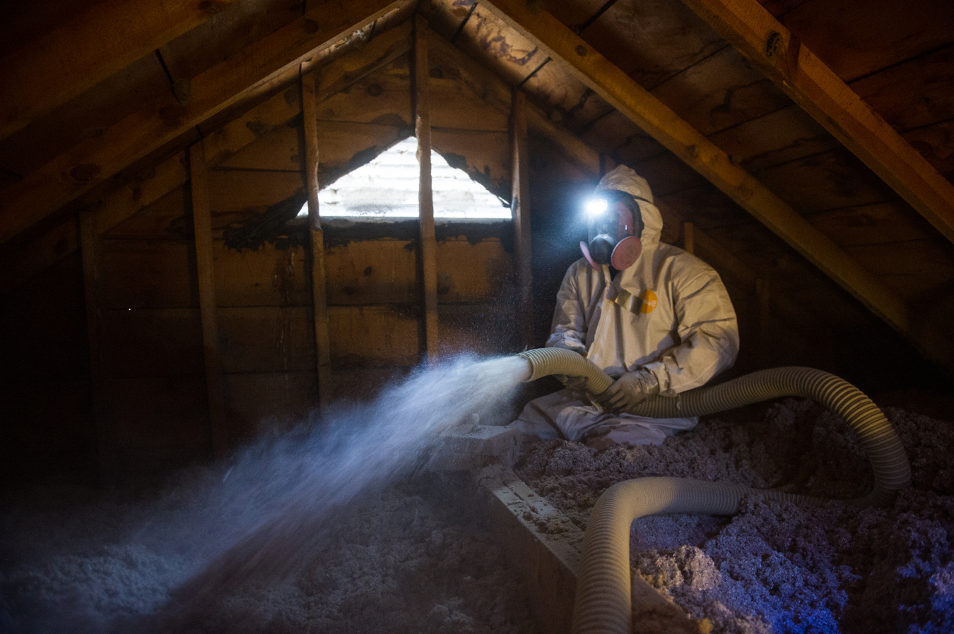 Weatherization worker insulating an attic.