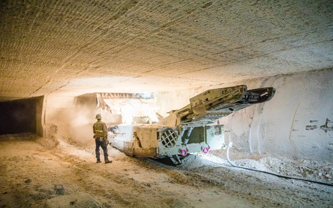 A worker operates a continuous mining machine 2,150 feet underground at the Waste Isolation Pilot Plant to create additional disposal rooms for transuranic waste. The rooms are carved out of 250-million-year-old bedded salt formation and measure 33 feet w