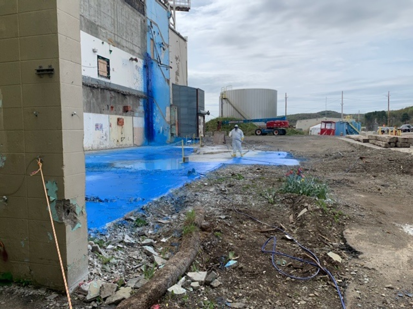 A worker at the West Valley Demonstration Project applies a fixative to the concrete slab of the former Main Plant Office Building to protect employees from potential asbestos.