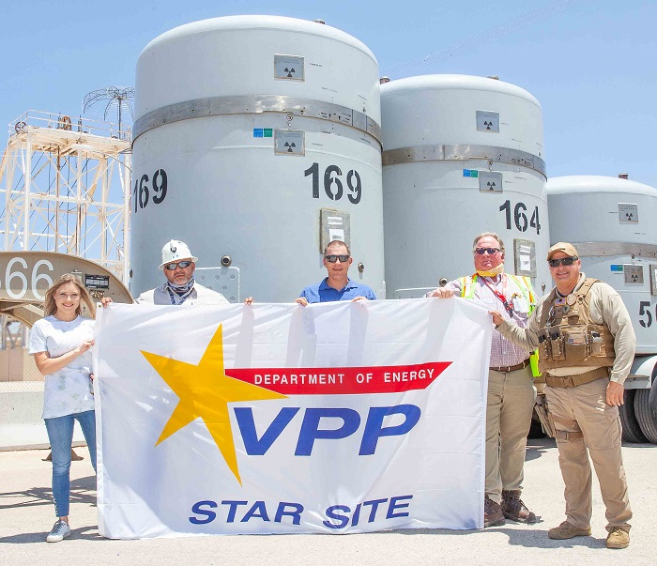 Nuclear Waste Partnership (NWP) President and Project Manager Sean Dunagan, center, helps unfurl the Voluntary Protection Program (VPP) Star site flag during a brief ceremony at the Waste Isolation Pilot Plant (WIPP) in late June.