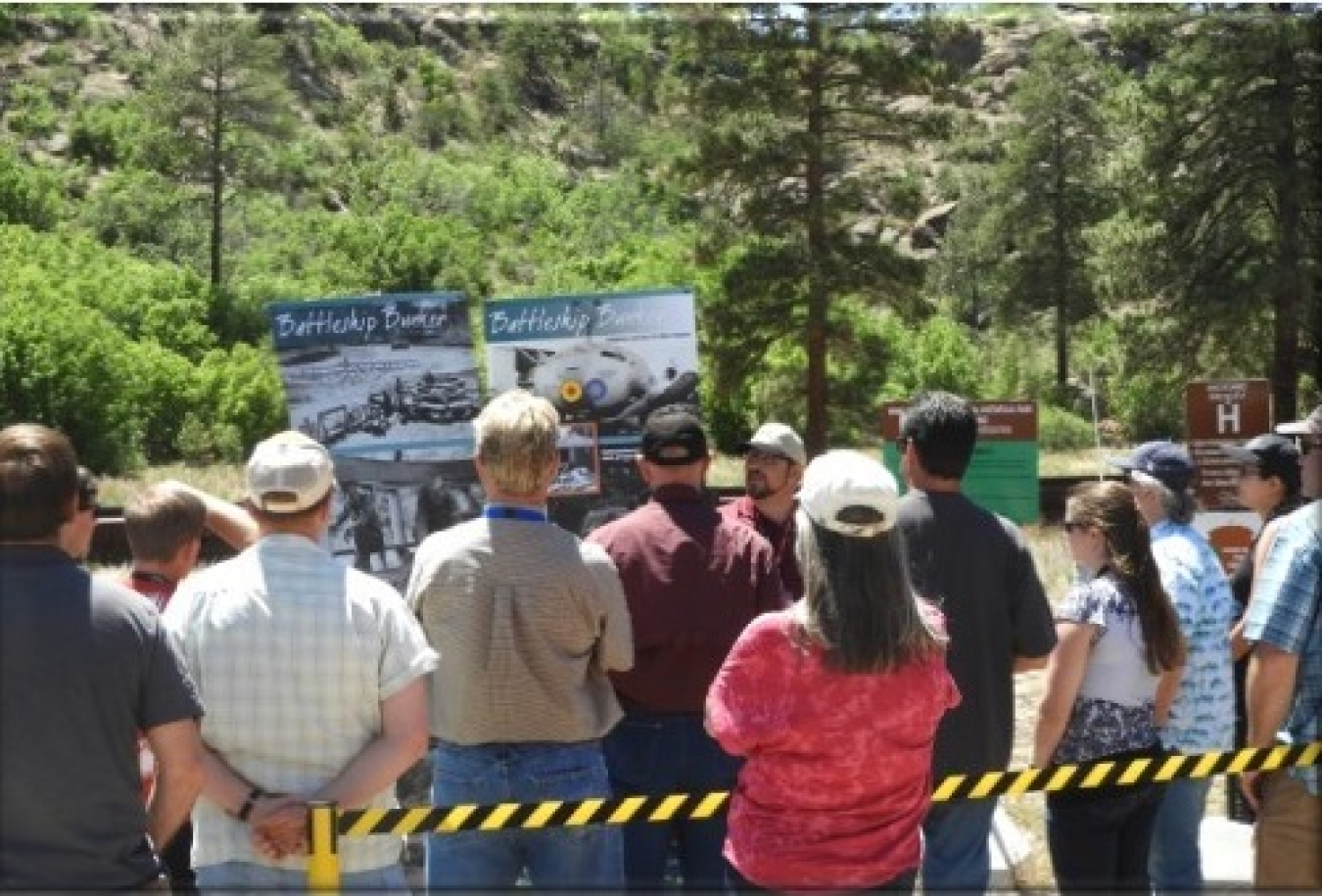 In this 2018 photo, visitors to the Pajarito Site at Los Alamos learn about Manhattan Project history. The site includes the Pond Cabin, Battleship Bunker, and Slotin Building used by scientists developing the plutonium bomb.