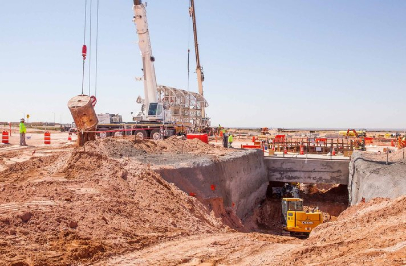 As a load of excavated dirt is dumped from the utility shaft, an excavator works on a sloped area that will hold the shaft's forced-air intake pipe, known as the plenum.