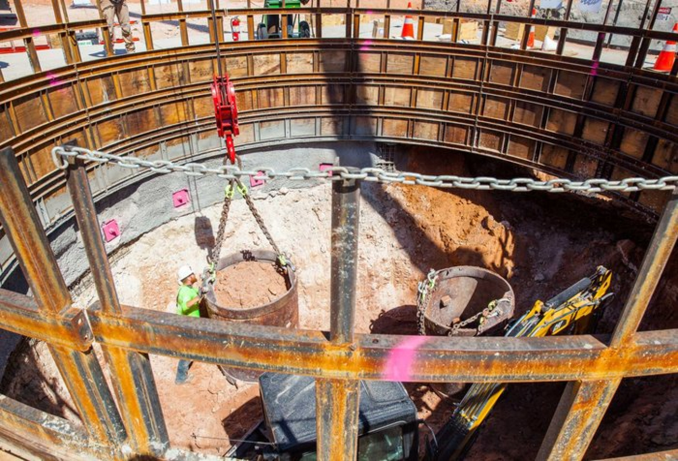 A worker gets a bucket ready for lifting in the Waste Isolation Pilot Plant's utility shaft as a mini excavator prepares to fill a second bucket with soil.