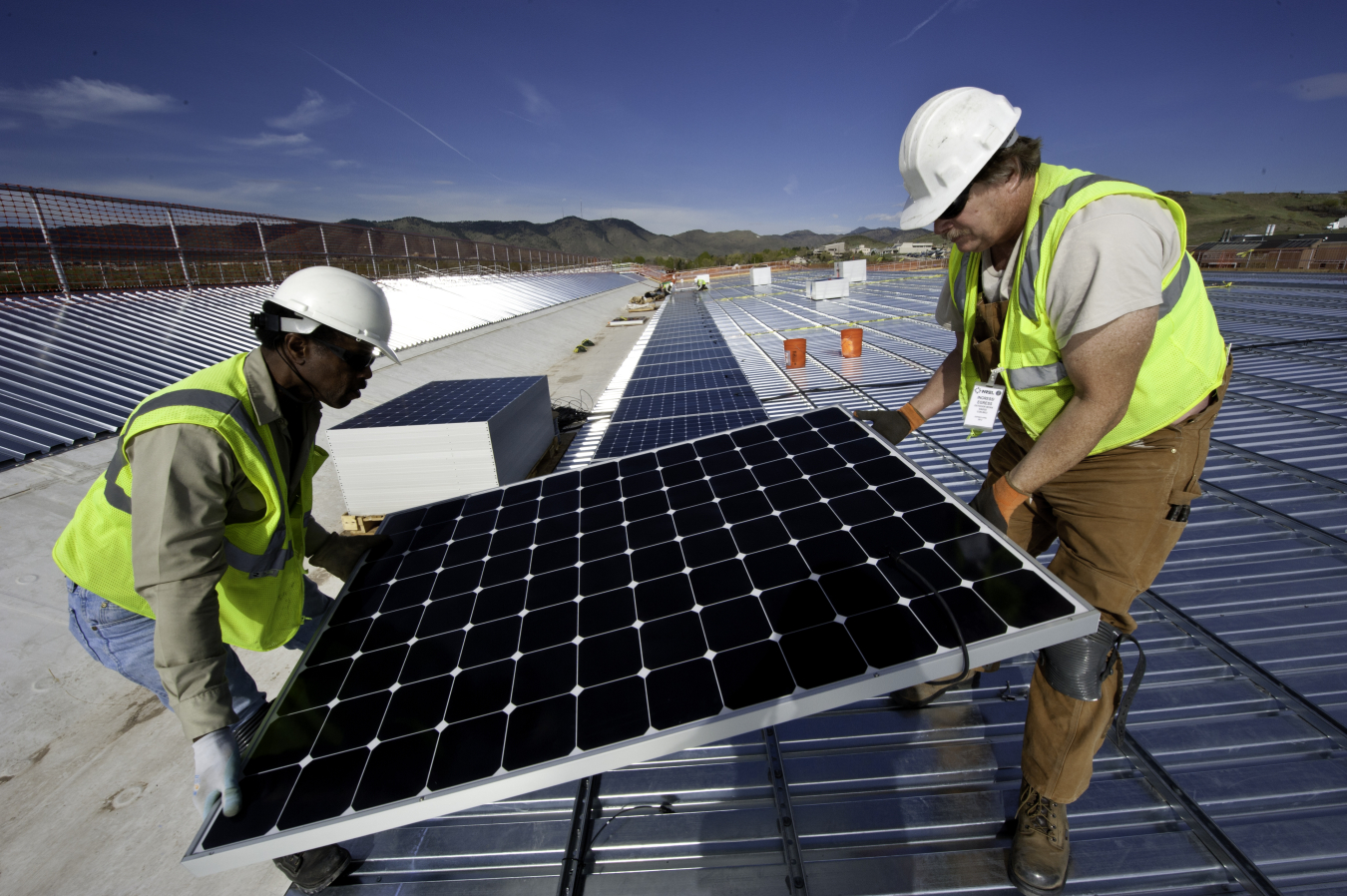 Workers installing PV modules on the roof of the parking structure on NREL's South Table Mountain campus