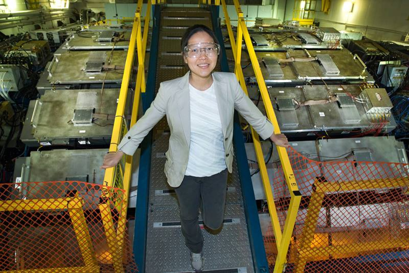 Lijuan Ruan stands atop the STAR detector at the Relativistic Heavy Ion Collider at Brookhaven National Laboratory. The silver Muon Telescope Detector components surrounding STAR’s magnet detect muons, the decay products of J/psi particles.