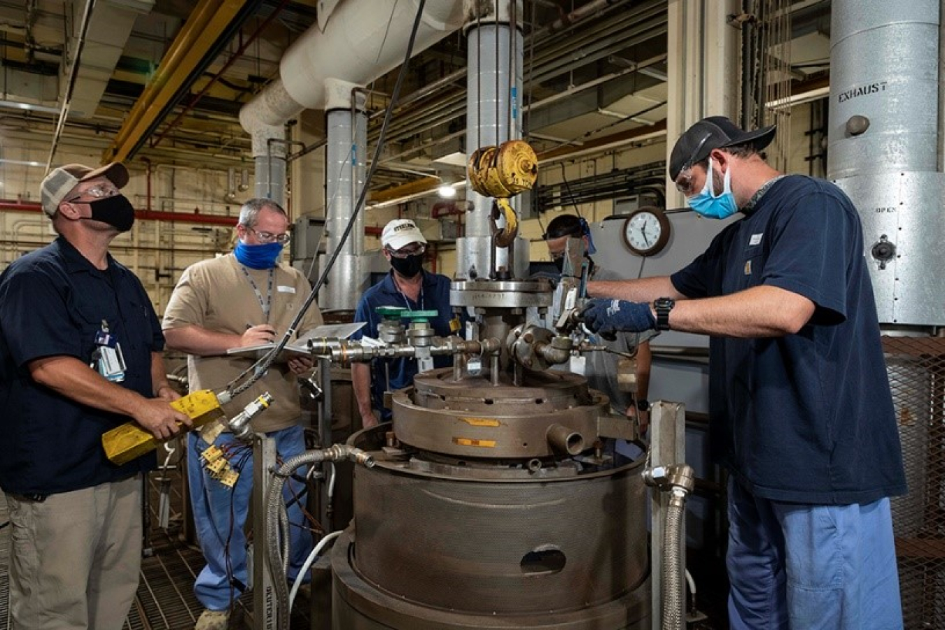 Y-12 National Security Complex chemical operators lower a reactor vessel into a furnace. The homogenization technology, developed by Y-12 scientists and engineers, is planned to be included in the site’s proposed new Lithium Processing Facility.