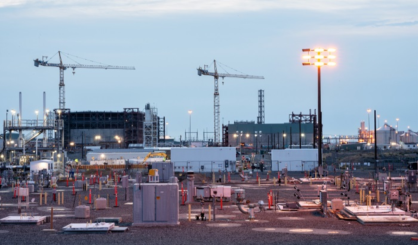 The white enclosures of the Tank-Side Cesium Removal (TSCR) system are visible adjacent to the Hanford Site’s AP Tank Farm. In the background is the Waste Treatment and Immobilization Plant, where waste pre-treated by TSCR will be heated to 2,100 degrees.