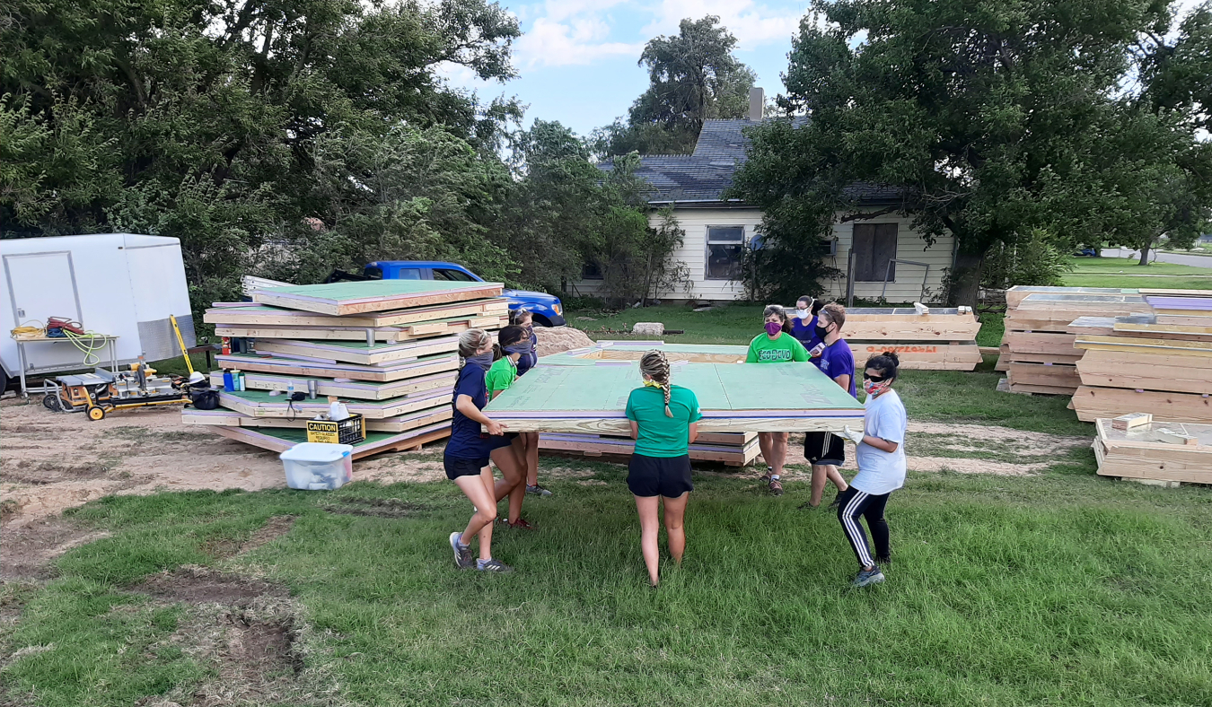 Kansas State University students competing in the Solar Decathlon Build Challenge move completed panels at the building site.