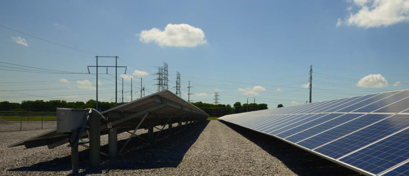 A solar photovoltaic plant with transmission power lines in the background