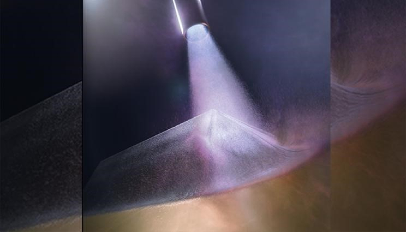 Lawrence Livermore National Laboratory: A cold-spray chamber is shown during deposition, with the nozzle at the top of the image and a near-full density sample being fabricated in the center.